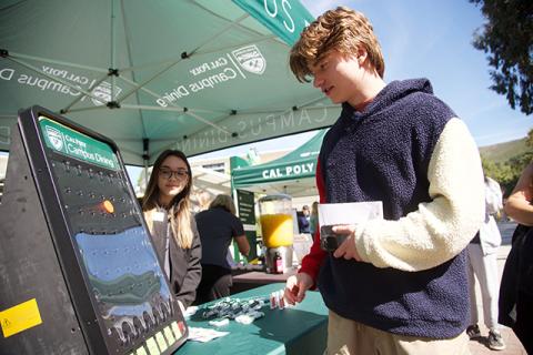 A student playing a game at a booth at a Cal Poly event.