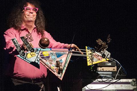 An image of Mark Applebaum standing with his instruments.