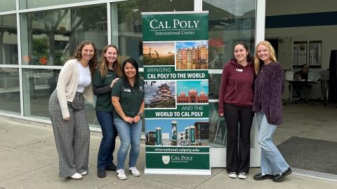A group of students standing around a sign outside of the International Center.