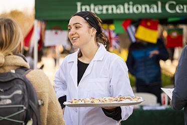  A student serving appetizers on a plate at a past A Taste of the World event.