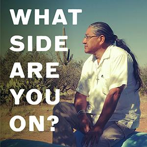 A graphic of an indigenous man sitting in the desert with the words “What Side Are You On?” over it.