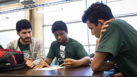 Two youth working on a project with a Cal Poly student.