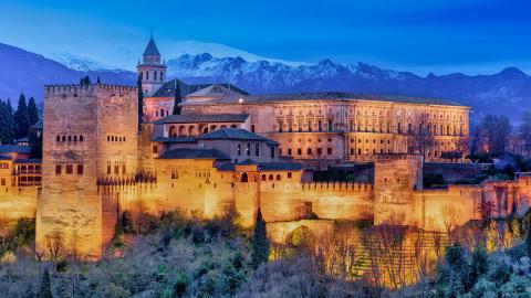 A castle in Granada with snow-capped mountains in the background.