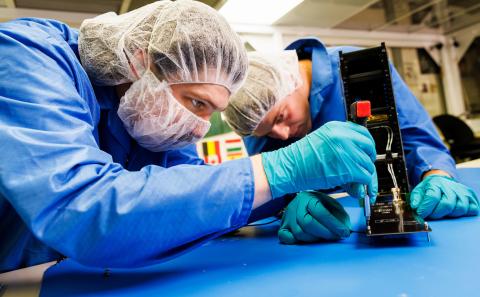 Students work on a CubeSat in a clean room on campus. 