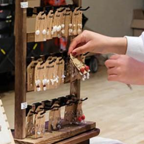 A person’s hands taking a pair of earrings from a vendor stand.