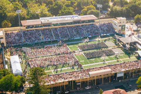 Aerial view of Cal Poly commencement at Alex G. Spanos Stadium, with graduates seated on the field and spectators filling the stands.
