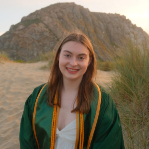 Ella Leback in her Cal Poly graduation gown in front of Morro Rock.
