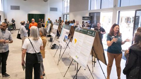 Participants gather among poster presentations at a symposium in a building on campus.