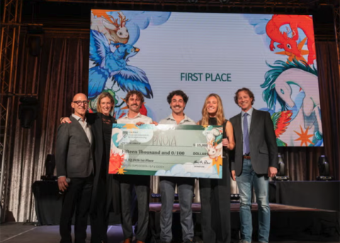 Students from the winning team standing with a large check and event presenters.