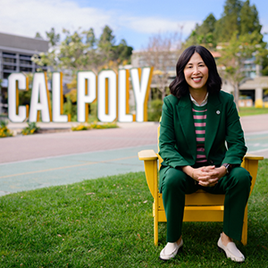 Susan Cheng sitting on a chair in front of the Cal Poly sign in the UU.