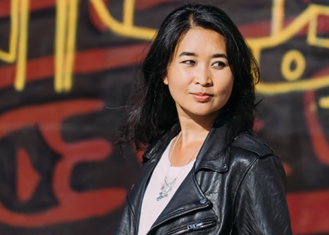 Artist and writer Thi Bui standing in front of a painted wall.