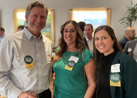 A group of three Cal Poly alumni wearing “Cal Poly Proud” stickers at a past event.