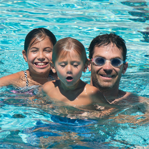 A father and his two children in the pool.