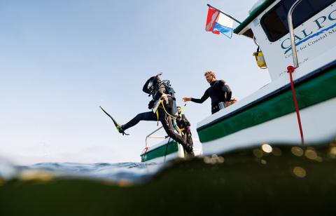 A student jumps into the ocean from a Cal Poly research vessel as part of the scientific diving course.