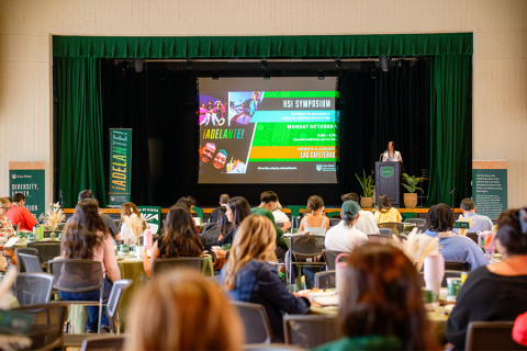 A speaker presenting on stage at a past ¡Adelante! Symposium.