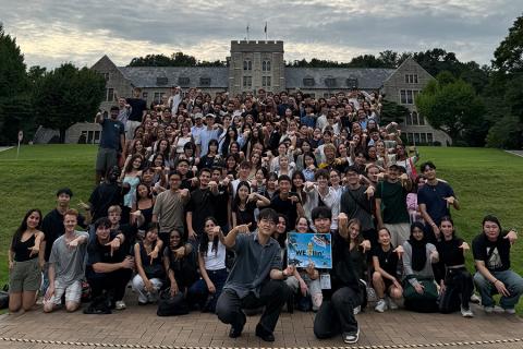 A group of students posing for a photo in front of a castle and lawn.