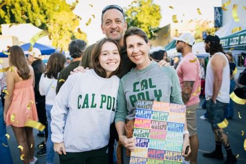 A Cal Poly student standing with her parents and smiling for the camera at SLO Farmers Market.