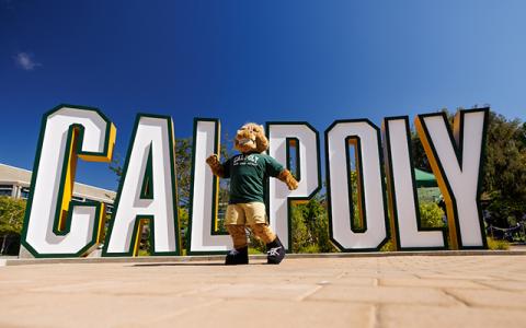 Musty the Mustang dancing in front of the Cal Poly sign in San Luis Obispo.