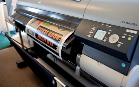 A large printer printing a colorful flyer.