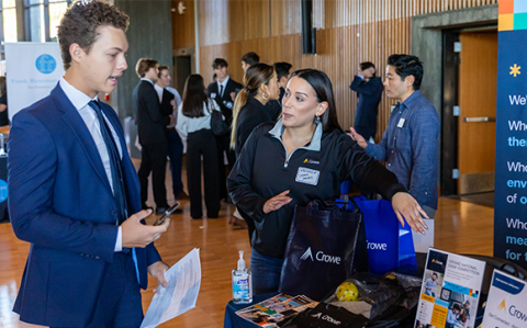 A student talking to a potential employer at a career fair booth.