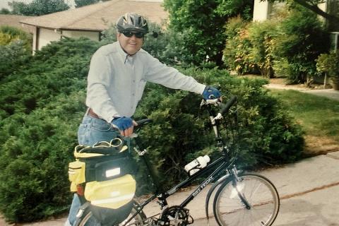 Stuart Goldenberg standing with his bicycle and wearing a helmet.