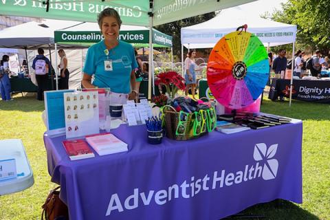 A Campus Health and Wellbeing employee standing at a booth at the health fair.