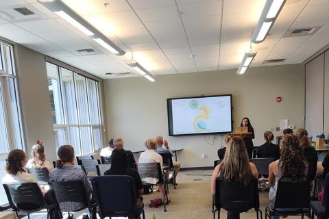 A person presenting to a group of people in a classroom.