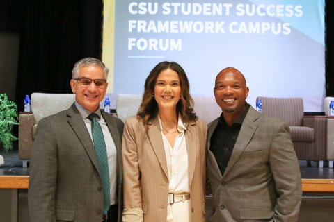 A faculty member standing with Cal Poly leadership at a forum.