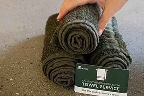 A hand picking up a towel from a pile with a sign that says "ASI Towel Service."