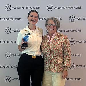 Bella Horne standing with her award and another person at an awards ceremony.