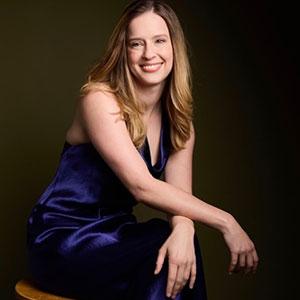 Elizabeth Dorman sitting with her arms crossed and smiling.