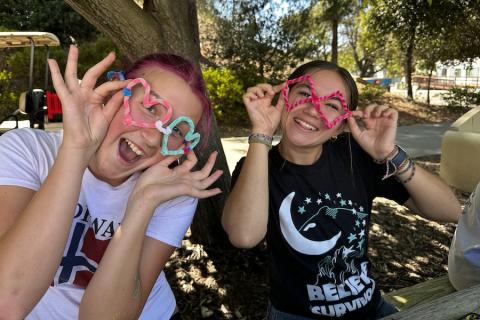 Two students wearing pipe cleaner glasses at a Domestic Violence Awareness Month event.
