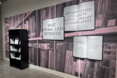 An installation at an art exhibit in the library with images of books and a bookshelf.