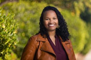 A woman in a leather jacket smiles outdoors in a portrait