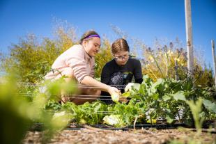 A Cal Poly student and a high school student work together in a garden.