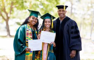 From left: Dionna Glover, Genesis Glover and Victor Glover, all wearing graduation regalia, smile for a family photo. Dionna and Genesis both hold their diplomas.