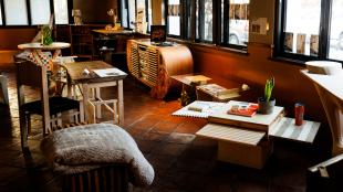 A collection of hand-made furniture items in a sunlit event space. 