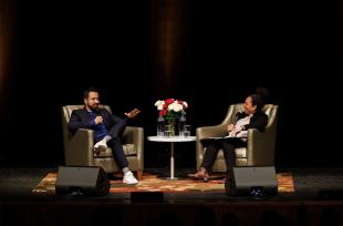 Actor Kal Penn sits in an armchair across from professor Denise Isom onstage at the Performing Arts Center. 