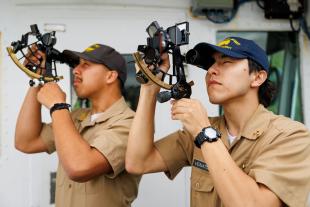 Tyler Venador uses a sextant next to another cadet.