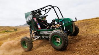 The Cal Poly Racing baja car skids over dirt below the hills of San Luis Obispo