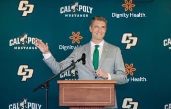 Cal Poly's new athletic director Carter Henderson gestures at a podium during an event announcing his position.