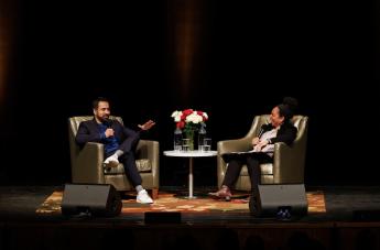 Actor Kal Penn sits in an armchair across from professor Denise Isom onstage at the Performing Arts Center. 