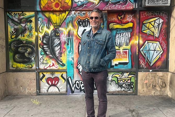 Alum Rich Toyon standing in front of a graffiti wall