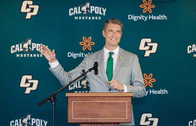 Cal Poly's new athletic director Carter Henderson gestures at a podium during an event announcing his position.