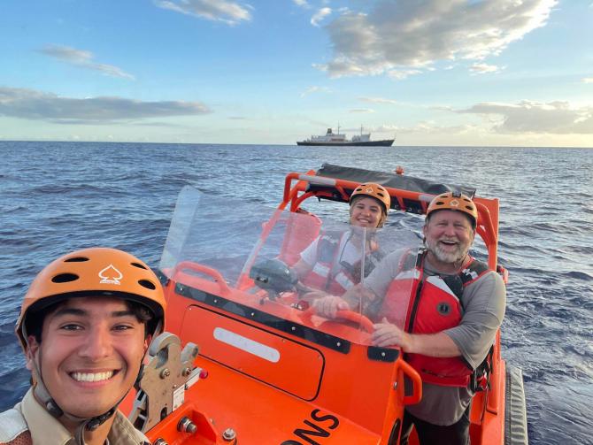Students and a professor on a marine transport training vessel with Training Ship Golden Bear in the background.