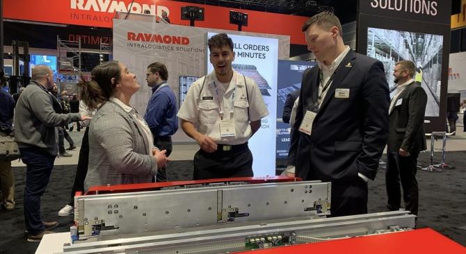 A student talking to two Raymond Intralogistics Solutions reps at a maritime conference.