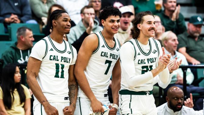 The Cal Poly men's basketball players smile on the sidelines at a game