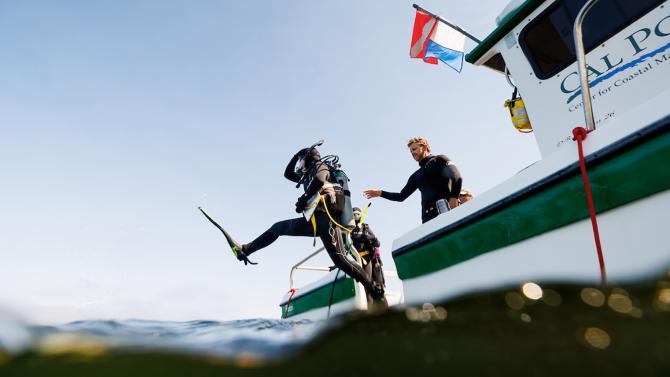 A student diver jumping into the ocean from a Cal Poly diving boat.